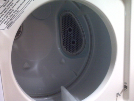 The inside of a Whirlpool dryer is shown, specifically focusing on the lint filter that's in the back in the upper-right part of the drum.