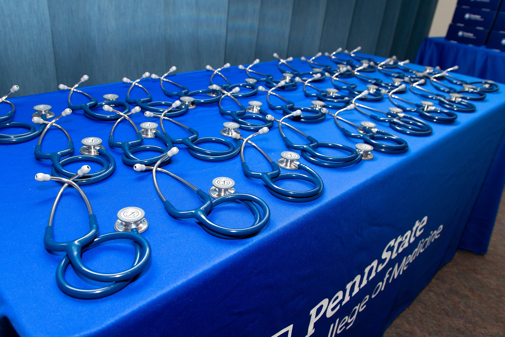 Stethoscopes lie on a table covered in a blue Penn State College of Medicine cloth