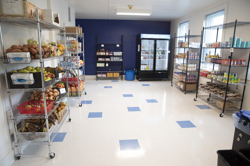 The Student and Employee Food Pantry interior has shelving units along the walls filled with food and a refrigerated case in the back right.